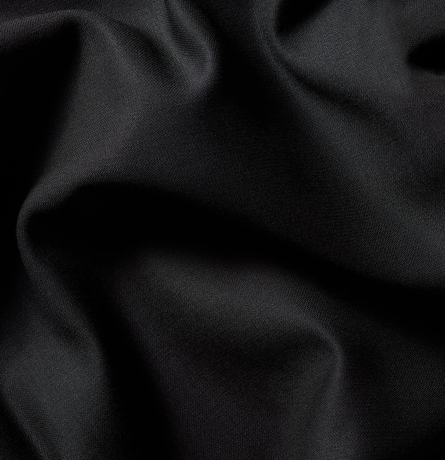 Close-up of black tuxedo fabric with subtle texture and light wrinkles.